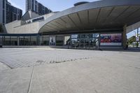 a person sitting at the bench in front of a mall that is empty of people