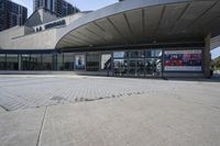 a person sitting at the bench in front of a mall that is empty of people