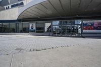 a person sitting at the bench in front of a mall that is empty of people