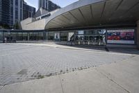 a person sitting at the bench in front of a mall that is empty of people