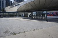 a person sitting at the bench in front of a mall that is empty of people