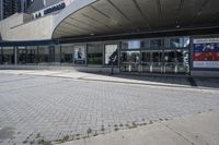 a person sitting at the bench in front of a mall that is empty of people