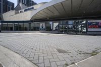 a person sitting at the bench in front of a mall that is empty of people