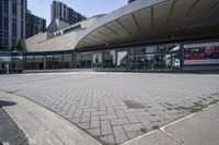 a person sitting at the bench in front of a mall that is empty of people