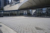 a person sitting at the bench in front of a mall that is empty of people