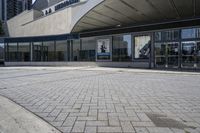 a person sitting at the bench in front of a mall that is empty of people