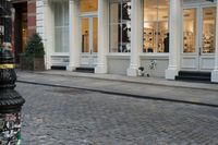 the fire hydrant outside of a brick storefront with shop windows and white pillars