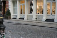 the fire hydrant outside of a brick storefront with shop windows and white pillars