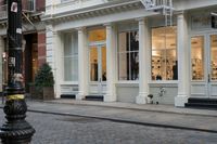 the fire hydrant outside of a brick storefront with shop windows and white pillars