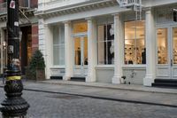 the fire hydrant outside of a brick storefront with shop windows and white pillars