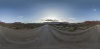 a 360 - view photograph shows the landscape from a dirt road through the desert with rocks in the distance