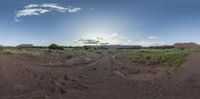 the view of a mountain that is reflected in a fish eye lens image of a dirt road with lots of dirt