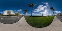 a panorama photo of some palm trees and the beach in front of them in front of buildings with sky