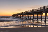 a long pier stretching over the ocean into the distance and a beautiful sunset in the background