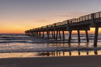 a long pier stretching over the ocean into the distance and a beautiful sunset in the background