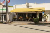 a sidewalk and sidewalk area in front of a restaurant with yellow awnings on both sides