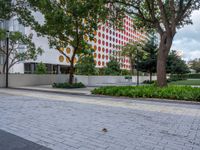 the sidewalk is full of colorful spots on a building in front of some trees and grass