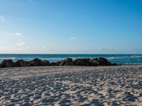 a beach and ocean on an overcast day with blue skies above the water's surface