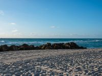 a beach and ocean on an overcast day with blue skies above the water's surface