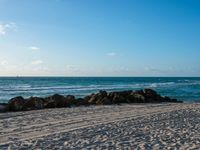 a beach and ocean on an overcast day with blue skies above the water's surface