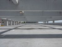 a cement walkway has a white structure with many windows and the pavement has a large hole on one side, where is concrete and the ceiling above which is visible with multiple floors