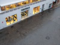 an overhead view of a store with the windows open at night with rain pouring down