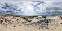 a 360 - shot photo of the beach with some water and rocks and a cloudy sky