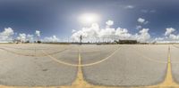 the view of a parking lot with clouds and sunshine in the background, with yellow lines