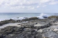 a man sitting on a surfboard with waves breaking in the distance on a rocky shore