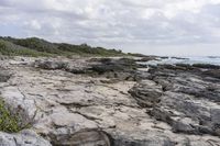 a man sitting on a surfboard with waves breaking in the distance on a rocky shore