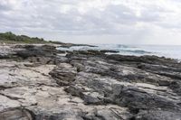 a man sitting on a surfboard with waves breaking in the distance on a rocky shore