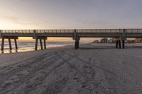 the beach is littered with footprints in sand as a bridge crosses over it into the distance