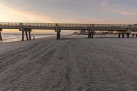 the beach is littered with footprints in sand as a bridge crosses over it into the distance