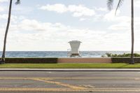 a building that has a lifeguard stand near the water on a beach side walkway