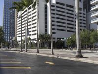 an empty city sidewalk surrounded by tall buildings and trees in a city square with cars and pedestrians passing on the road