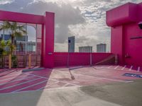 a view of the sky in a bright pink building, from a parking lot with a large parking space