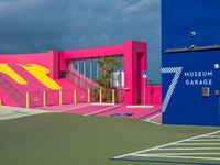 a pink and blue museum garage on a tennis court next to stairs with a red box at one end