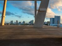 a bench sitting on top of a concrete floor in a parking lot with cityscape in the background