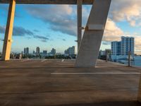 a bench sitting on top of a concrete floor in a parking lot with cityscape in the background