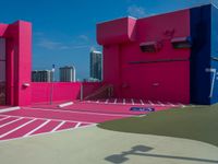 a person with a tennis racquet in front of a building with bright pink walls