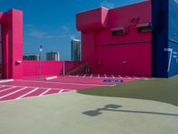 a person with a tennis racquet in front of a building with bright pink walls