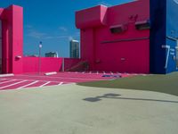 a person with a tennis racquet in front of a building with bright pink walls