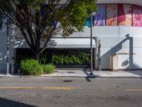 a parking meter sitting next to a road under trees and a building with a sign