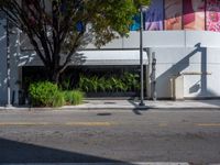 a parking meter sitting next to a road under trees and a building with a sign