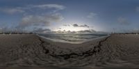 a fish eye view looking out at the ocean at sunset over the beach and houses