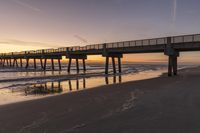 the long beach has some people walking near it at sunset over the water and on the shore