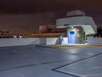 a building with parking spaces underneath it at night with purple skies behind the sky and a door in between two