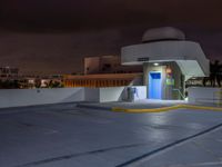 a building with parking spaces underneath it at night with purple skies behind the sky and a door in between two