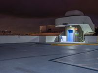 a building with parking spaces underneath it at night with purple skies behind the sky and a door in between two