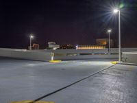 an empty parking lot near a city at night with buildings in the background and a yellow arrow indicating the corner